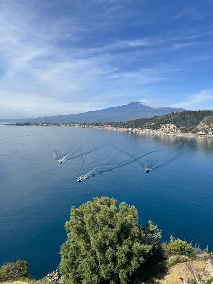 A coastal town with boats on the water, a mountain in the background, and a clear sky. 3