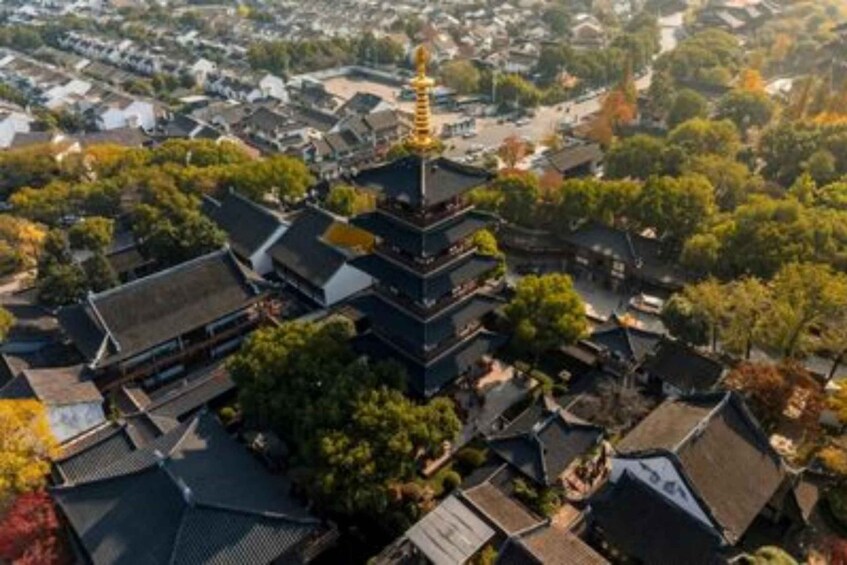 A traditional multi-tiered pagoda surrounded by residential buildings and autumn foliage. 1