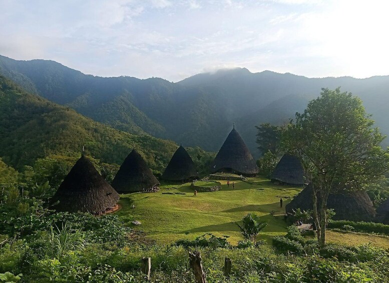 A mountainous landscape with thatched-roof huts and lush greenery. 2