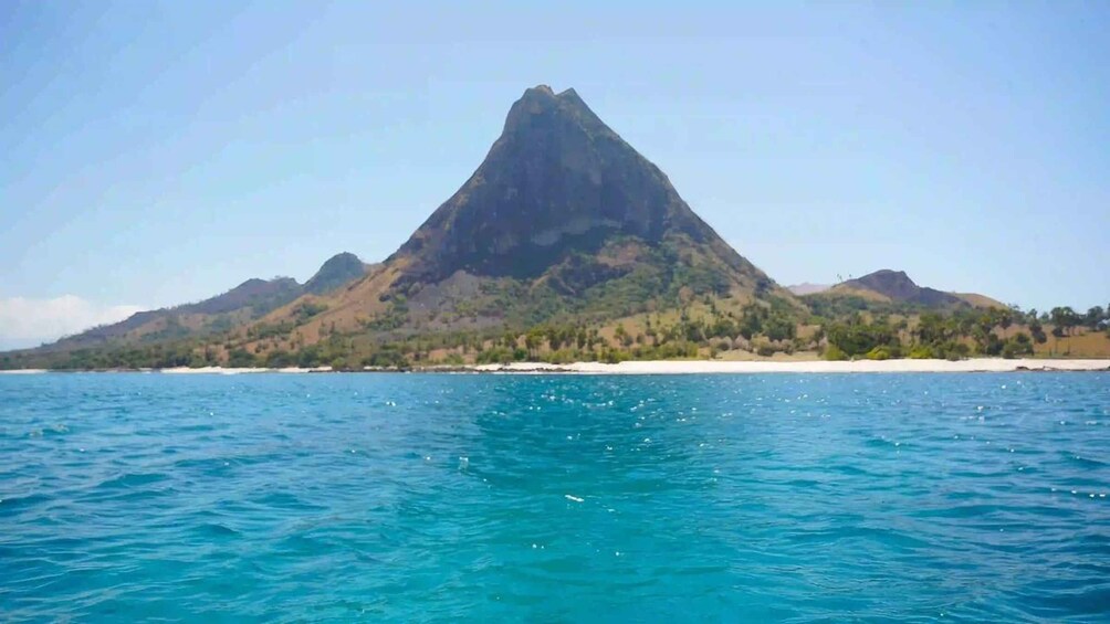 A mountain range with a prominent peak, a sandy beach, and calm blue waters. 3