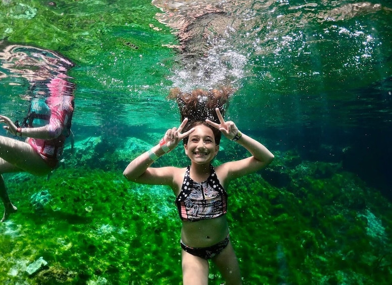 A person underwater with a snorkel, surrounded by clear green water and aquatic plants. 3