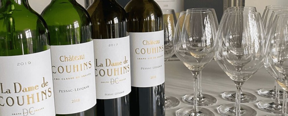 Bottles of Chateau Couhins wine and empty wine glasses. 3