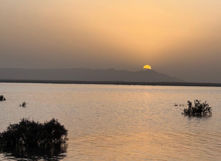 A sunset over a calm lake with mountains in the background. 1