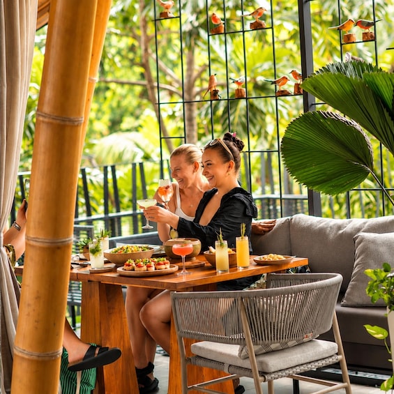 Two people dining at an outdoor restaurant with a tropical setting, bamboo pillars, and decorative bird figures. 5