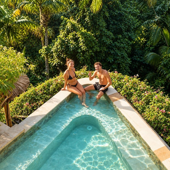 A man and a woman sitting on the edge of a swimming pool surrounded by lush greenery. 3