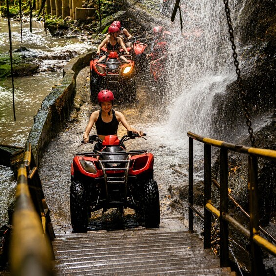 People riding ATVs down a water slide. 1