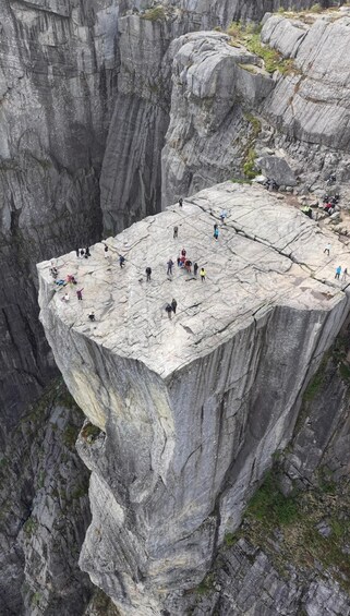 A group of people on a large rock ledge with steep cliffs below. 5