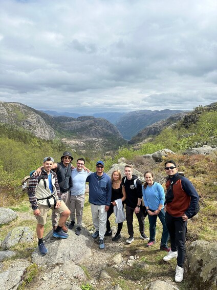 A group of people standing on a rocky outcrop with a mountainous landscape in the background. 2