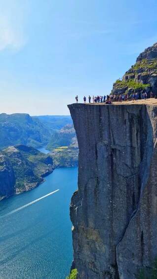 A group of people standing on a cliff edge overlooking a deep valley and a river. 1