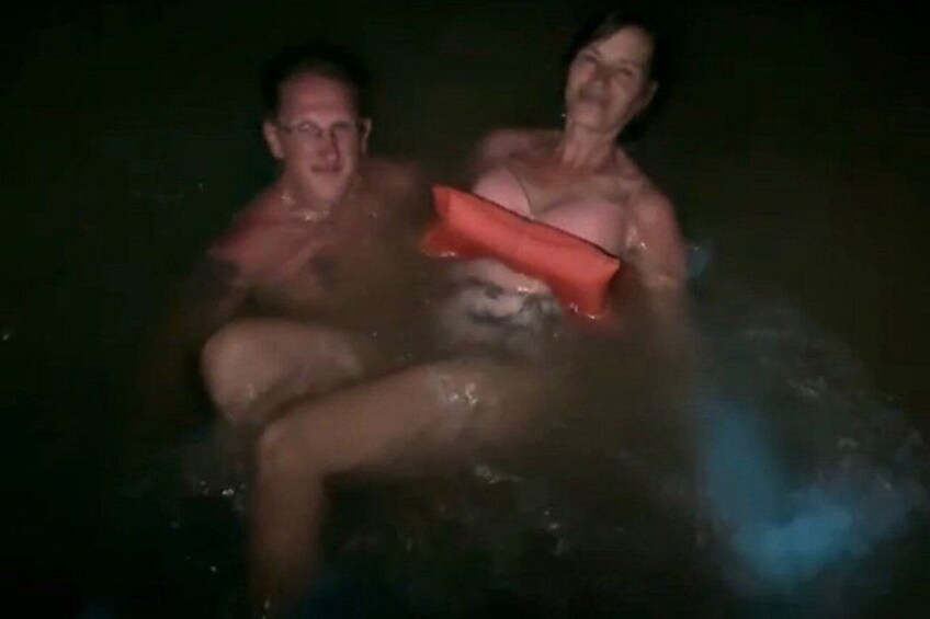 Two people in a water body, possibly a hot tub, with a red object between them. 4
