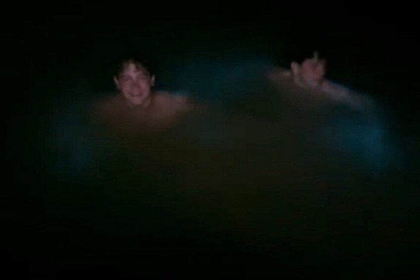 Two people in a dark environment, possibly a swimming pool, with blue lighting. 3
