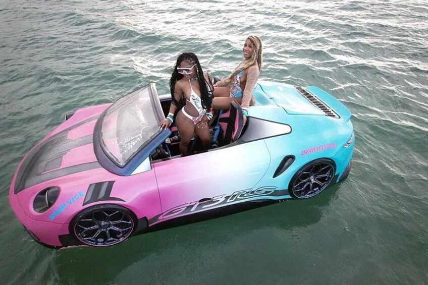 A pink and blue convertible car on water. 1
