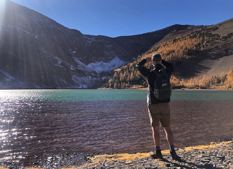 A person standing by a lake with mountains in the background. 1
