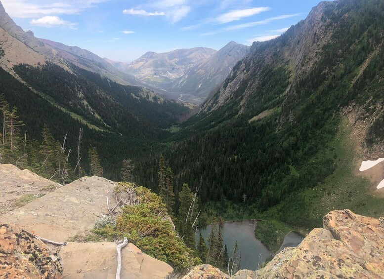 A mountainous landscape with a valley, a lake, and a rocky foreground. 2