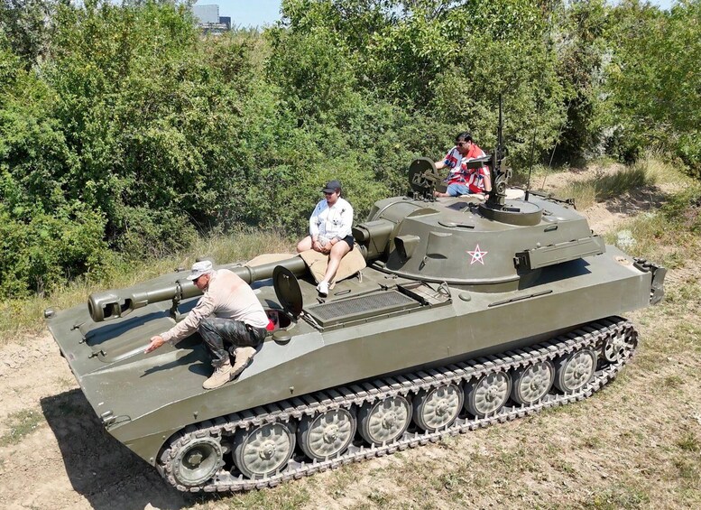 A military tank with tracks and a large gun, surrounded by greenery and trees. 3