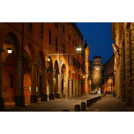 A nighttime street with historic buildings, arches, and street lamps. 1
