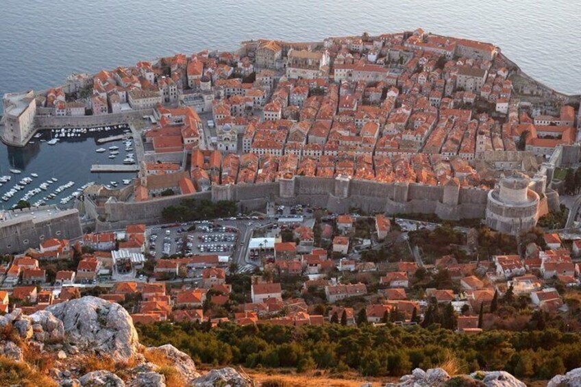 A coastal city with a historic fortification, red-roofed buildings, and a harbor. 2