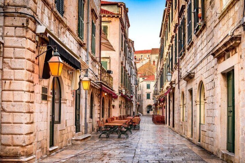 A cobblestone street lined with historic buildings, a wooden bench, and traditional street lamps. 5