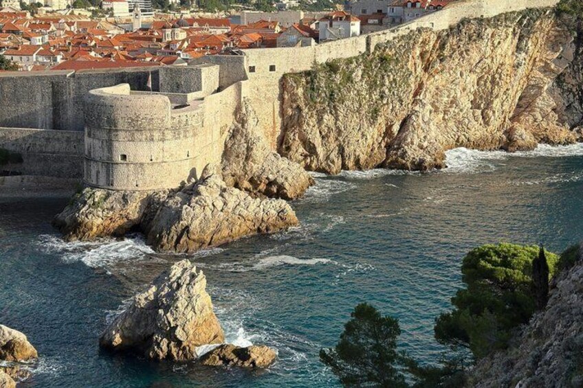 A coastal city with a historic stone wall and rocky shoreline. 3