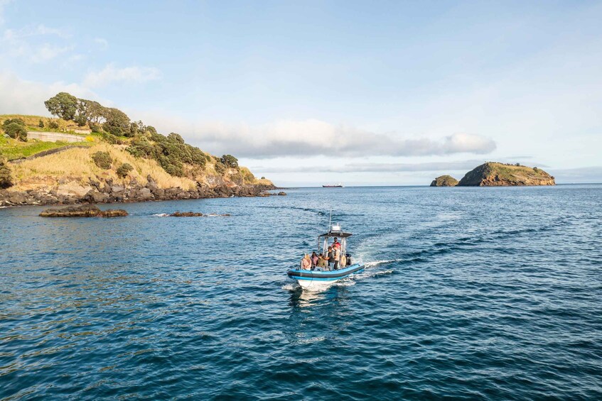 A boat on calm waters with rocky shores and distant islands. 1