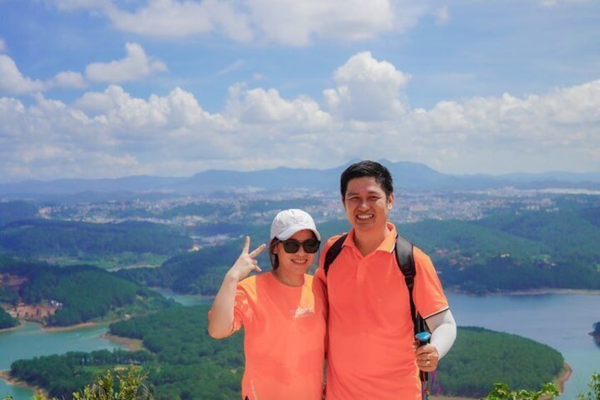 Two people in orange shirts standing on a hill with a lake and mountains in the background. 4