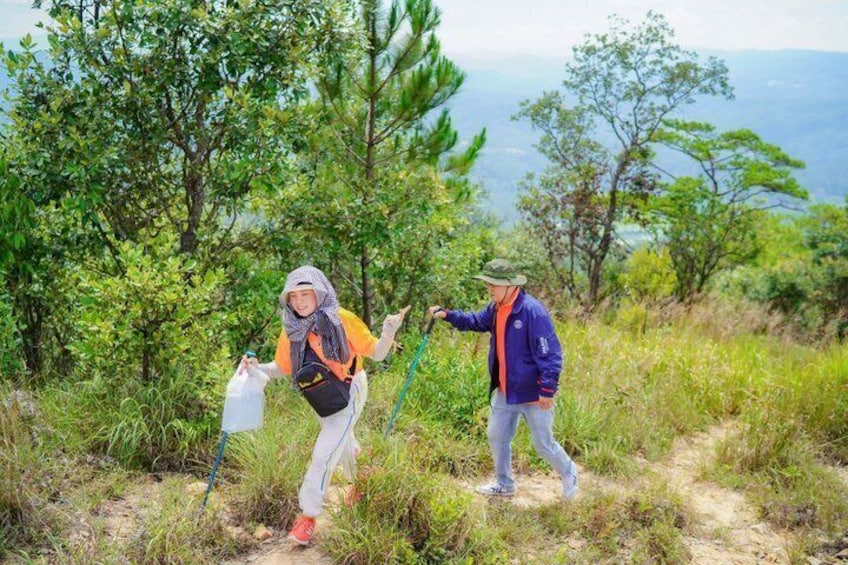 Two people hiking on a trail with trees and a distant view of mountains. 3