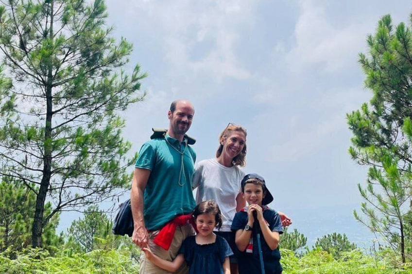 A family of four in a forested area with pine trees and a clear sky. 5