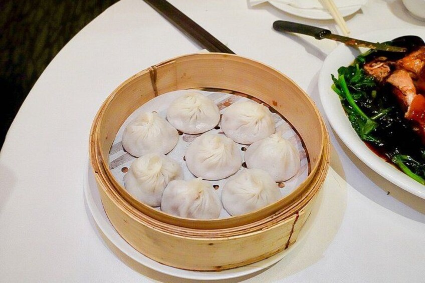 A bamboo steamer with dumplings on a white table. 2
