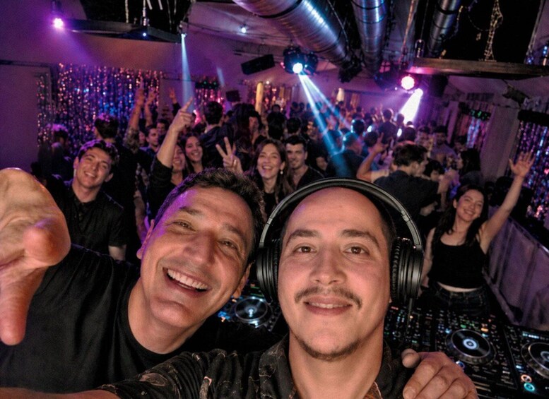 A crowded indoor event with people dancing and a DJ booth in the background. 5