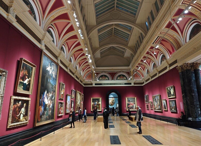 An art gallery with red walls, classical architecture, and numerous paintings on display. 1