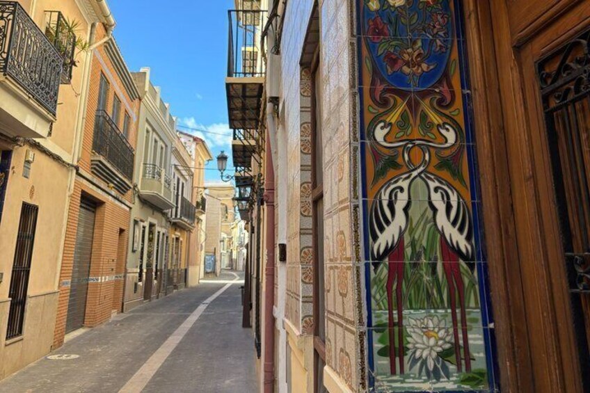 A narrow street with colorful tiled walls and balconies. 5