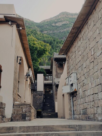A narrow alleyway flanked by stone buildings with a staircase leading to a traditional house. 2