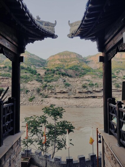 A traditional pavilion overlooking a river with a mountainous backdrop. 4