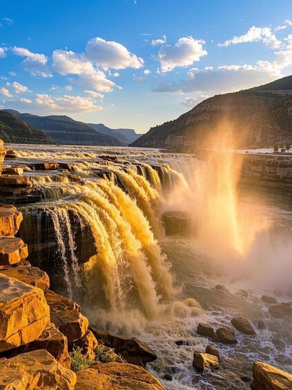A waterfall cascading over rocky ledges with a clear sky above. 5