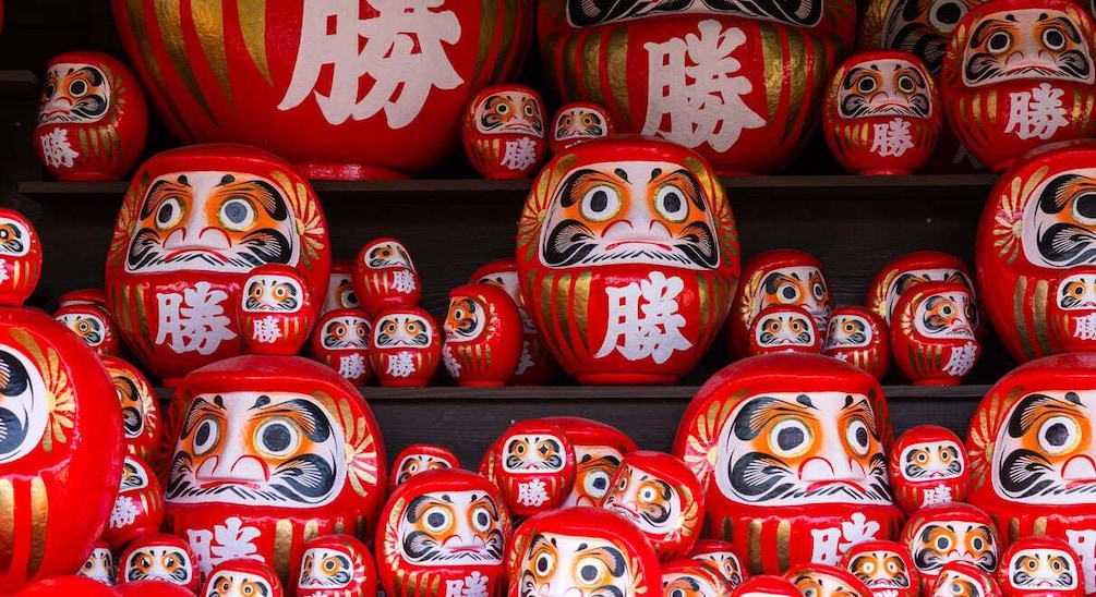 A collection of red and gold Japanese dolls with facial expressions. 1