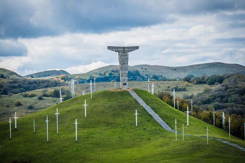 A hill with a central monument and multiple swords arranged in a circle. 1