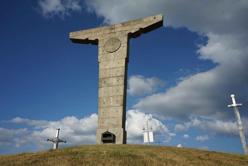 A large stone cross monument on a hill with a clear sky. 2