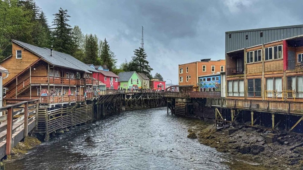 A wooden bridge over a river, colorful buildings, and a cloudy sky. 3