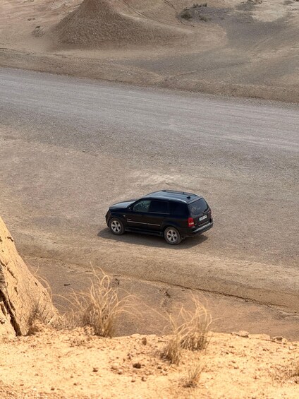 A black SUV on a dirt road in a desert landscape. 3
