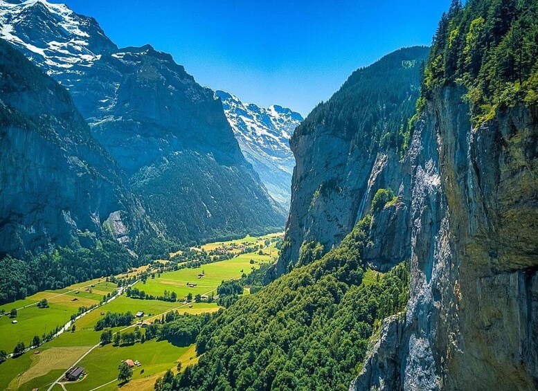 A valley with a mountain range, a river, and a small settlement. 1