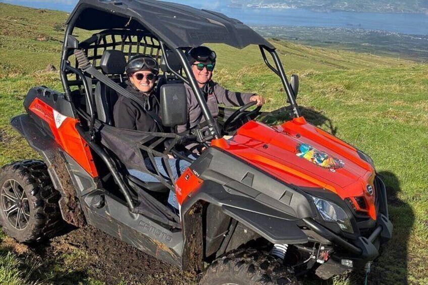 A red ATV with two people in a grassy field. 4