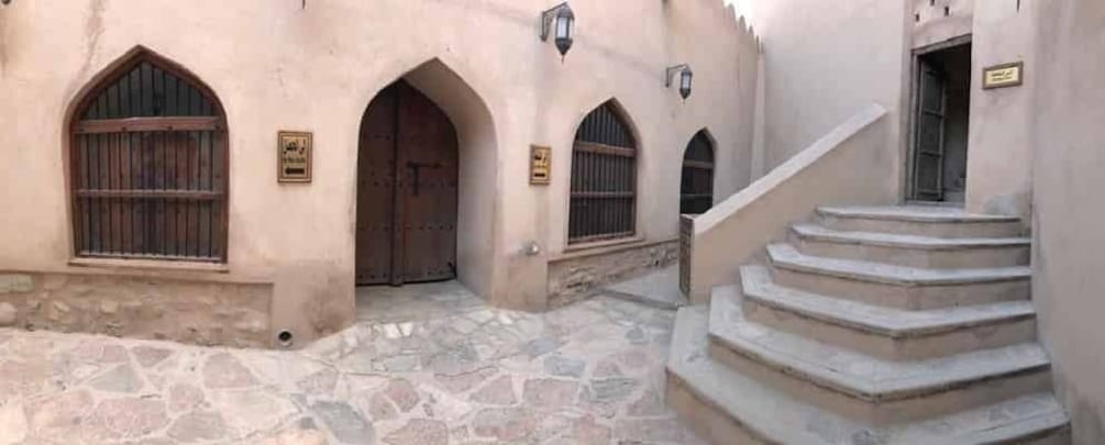 A stone courtyard with arched doorways and a staircase. 4