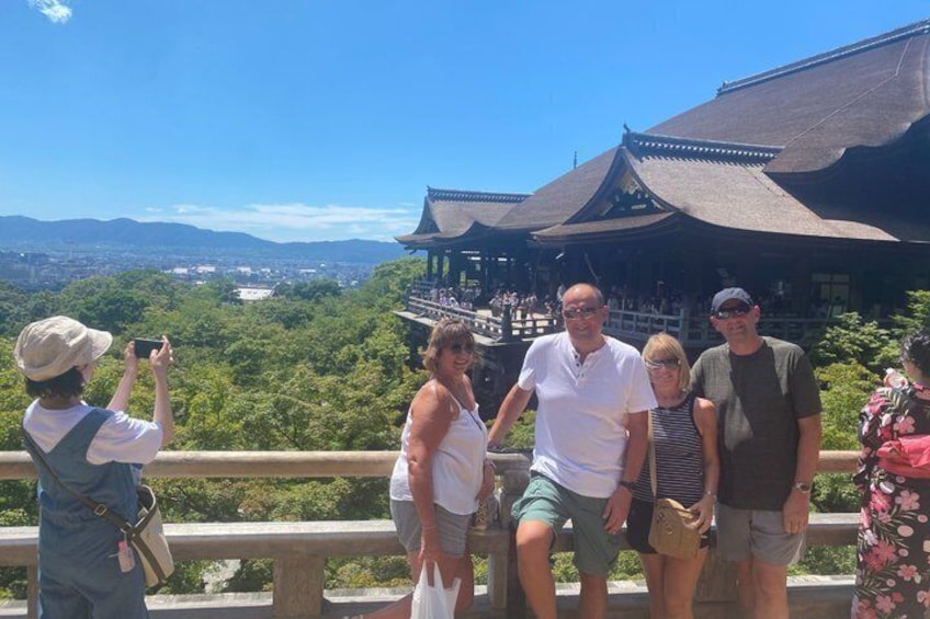 Un gruppo di persone scatta una foto da un punto panoramico con vista su un edificio tradizionale e una vegetazione lussureggiante. 4