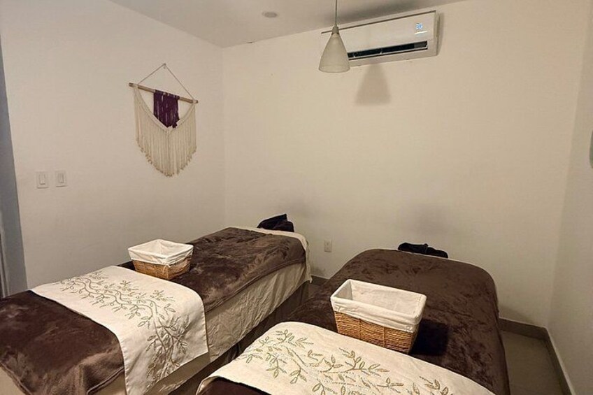 A room with two beds, a hanging macrame decoration, and an air conditioning unit. 2