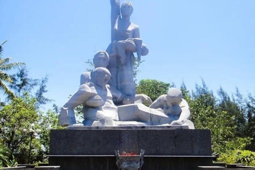 A stone sculpture of figures in various poses, set against a clear sky. 5