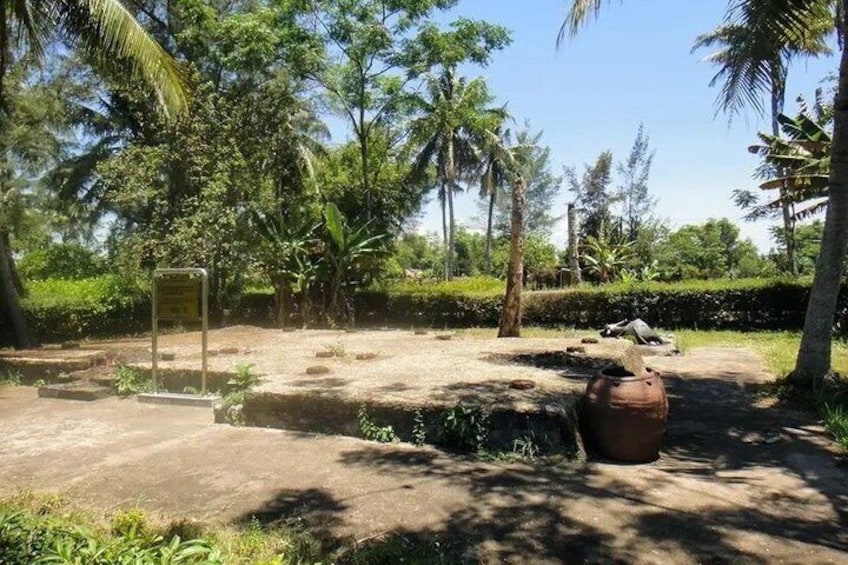 A natural park with a large stone structure, a sign, and a large pot. 3