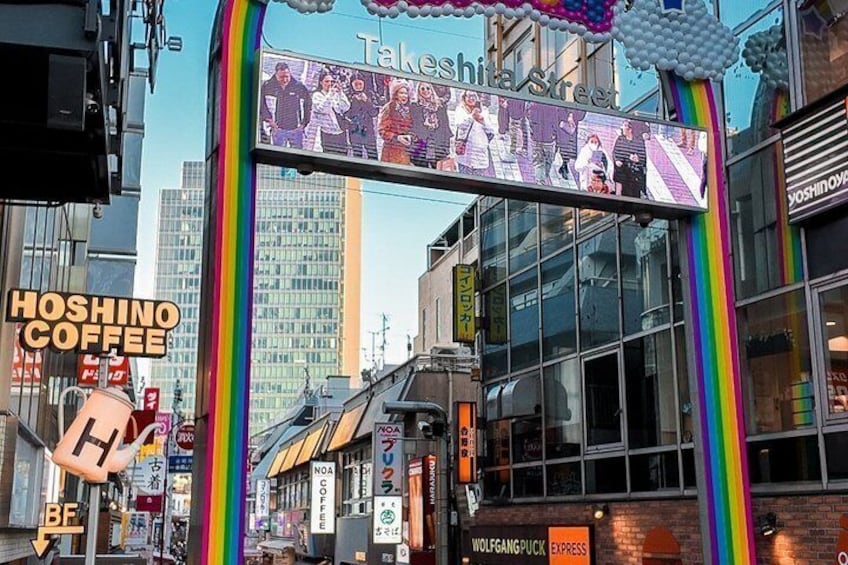 A street scene with a rainbow arch, a Takeshiba Street sign, and storefronts including Hoshino Coffee. 4