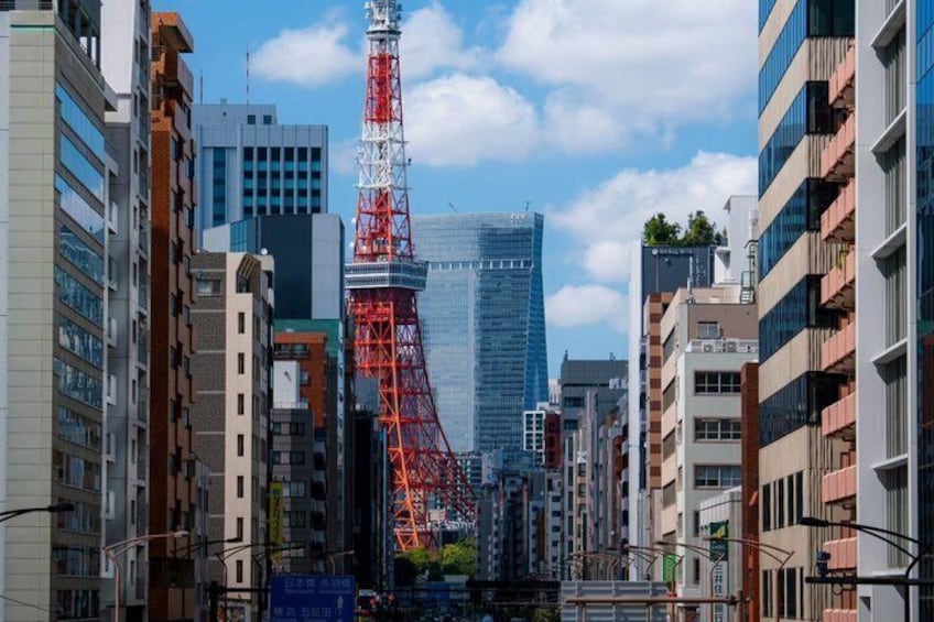 A cityscape with modern buildings, a prominent red tower, and a clear blue sky. 3