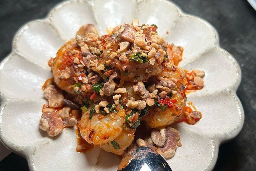 Een bord met garnalen, saus en garnering. 5