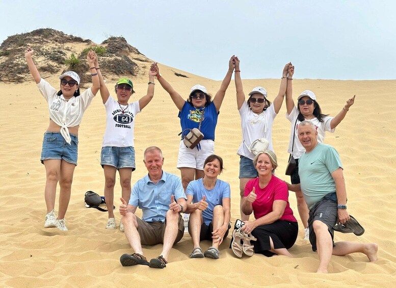 A group of people in a desert setting with sand dunes in the background. 4